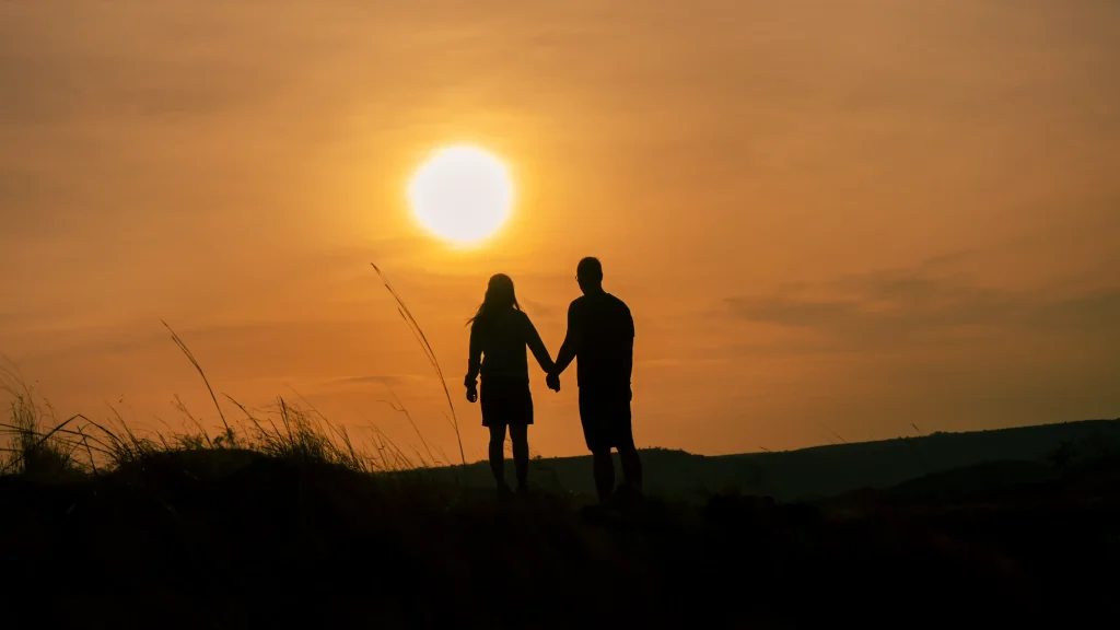 Silhouette of a couple holding hands at sunset on Persaudaraan Hill, Sumba