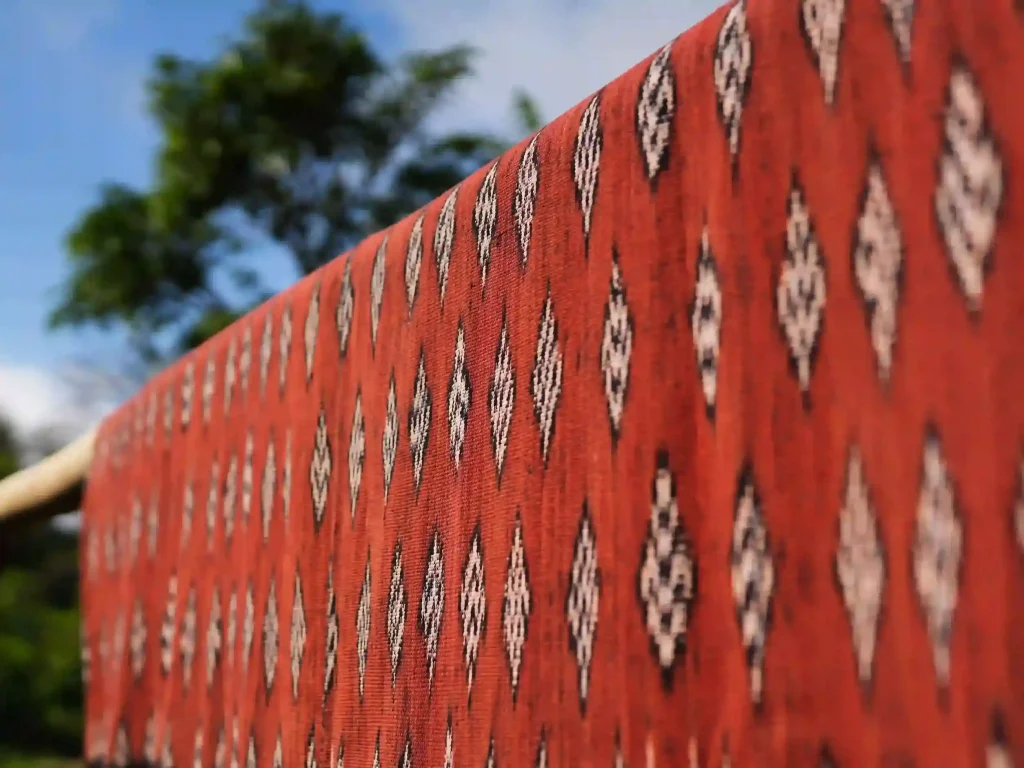 Red Sumba tenun cloth hanging outdoors among trees